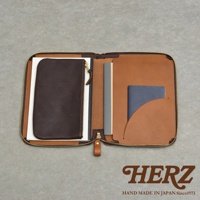 一個打開的棕色皮革記事本收納包，內部有幾個隔層，包含一個深棕色拉鍊小包、一本灰色的筆記本和一本藍色的護照。