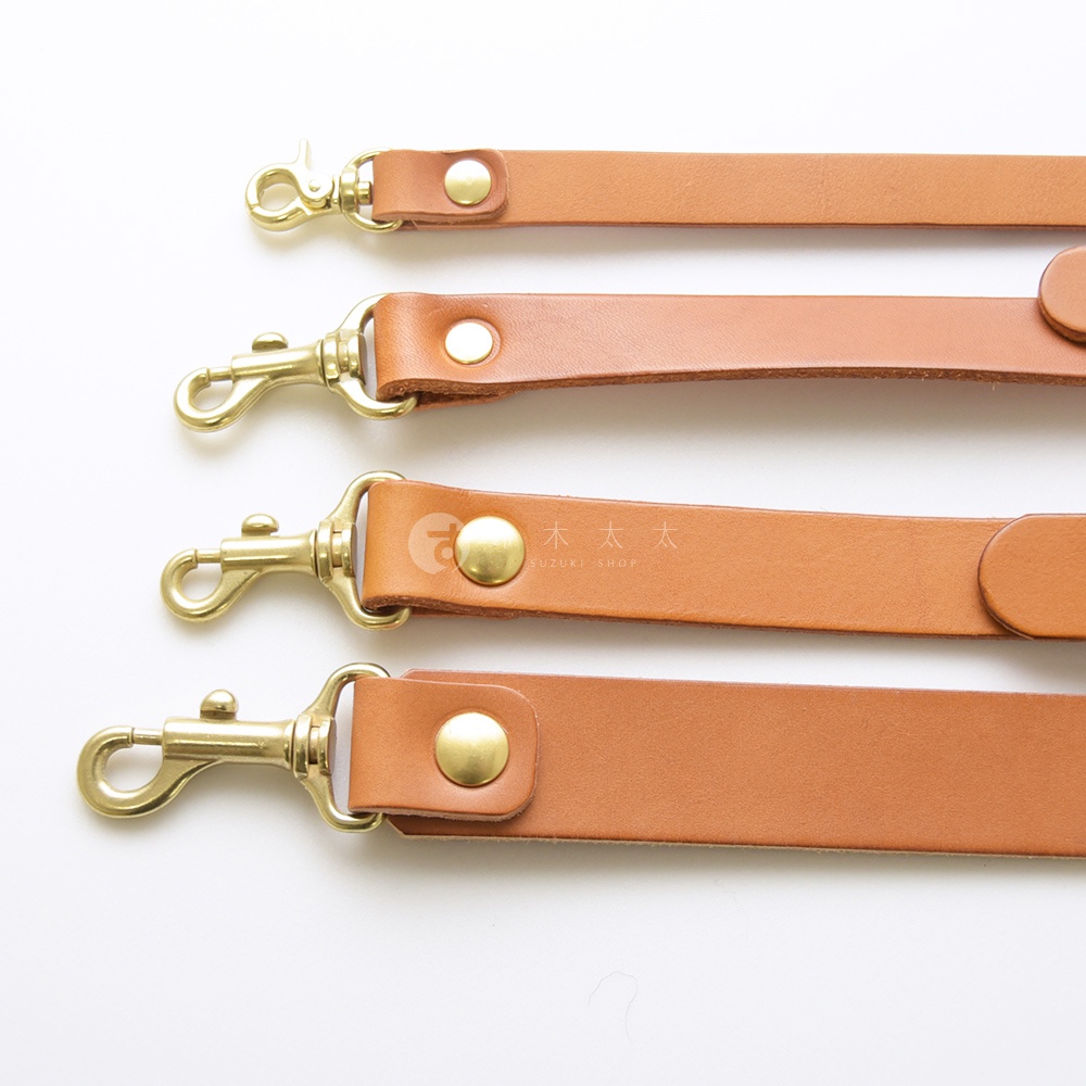 職人手作皮革肩背帶，帶有黃銅釦環，以不同寬度呈現。
