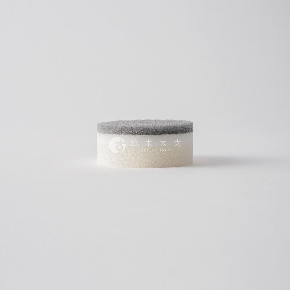 圓柱形狀的洗碗海綿，上方為灰色磨砂材質，下方為白色泡綿，中間印有日文「鈴木太太」及英文「SUZUKI SHOP」字樣。