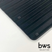 一張黑色食物快速冷卻盤的特寫，盤面帶有平行凹槽，四個角落下方有白色防滑墊。