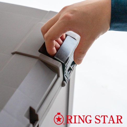 灰色塑膠儲物箱，一個手正在操作其黑色扣環。箱體表面有紋理，左側可見部分提把。