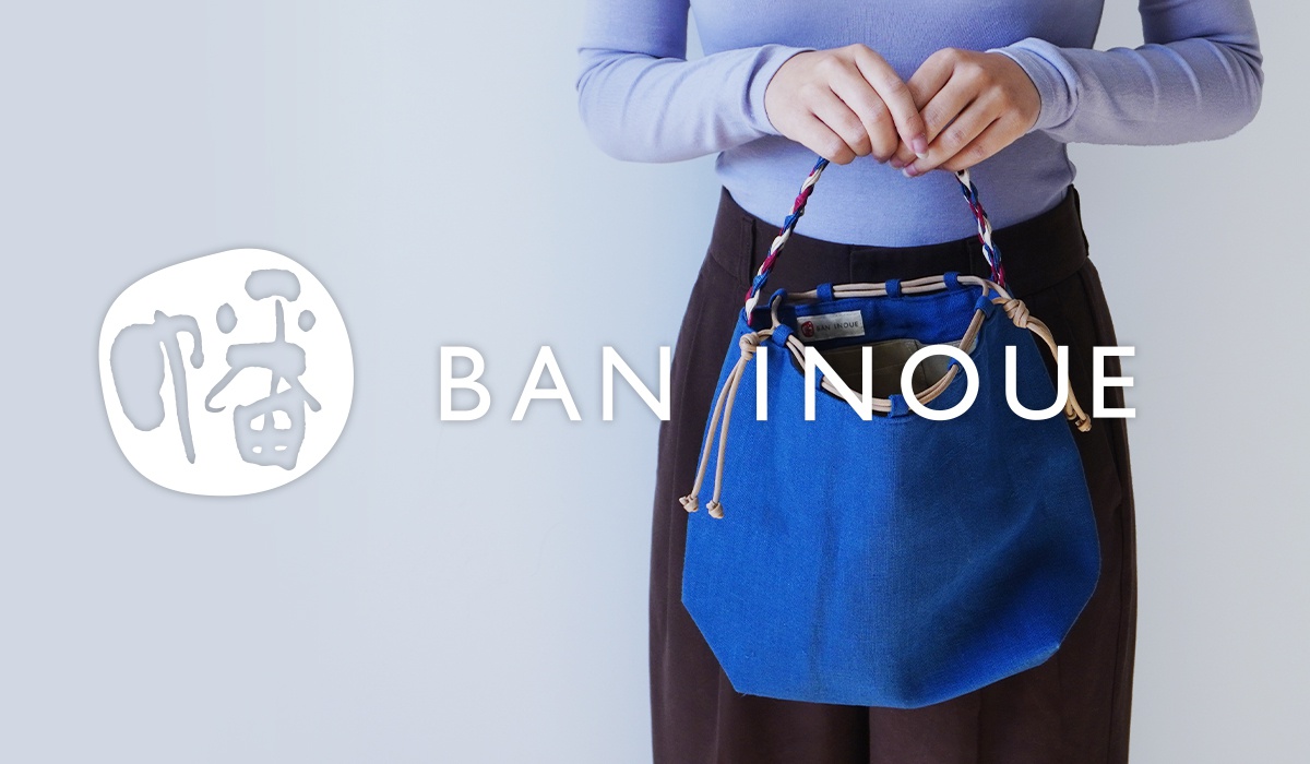 一個人拿著一個藍色的束口袋包，包上有日文字和品牌名稱 BAN INQUE。