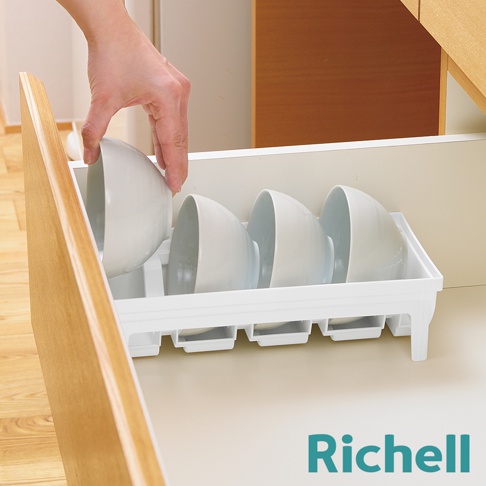手正在將一個白色碗放入抽屜式的白色碗架中，碗架內已擺放了三個白色碗。