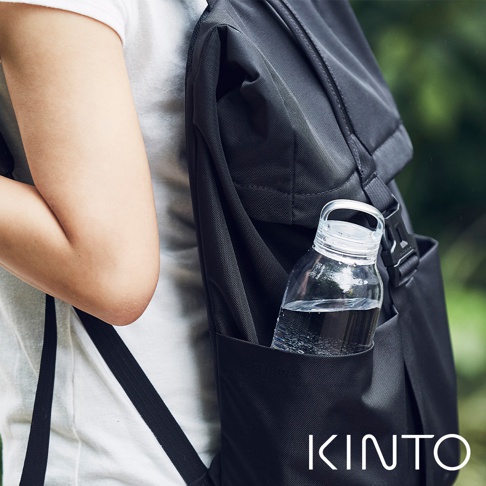 一個裝有水的透明玻璃瓶，瓶蓋為透明塑膠，置於黑色背包的側邊口袋中。