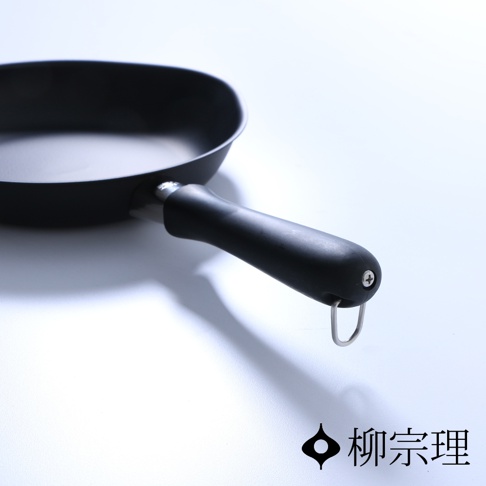 黑色岩紋單手鐵鍋，附有防滑黑色手柄，鍋身為金屬材質，手柄末端有掛環設計。