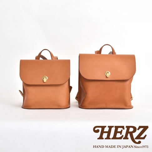 兩款棕色皮革翻蓋迷你後背包，尺寸不同，皆配有金色旋轉鎖扣和皮革提把。