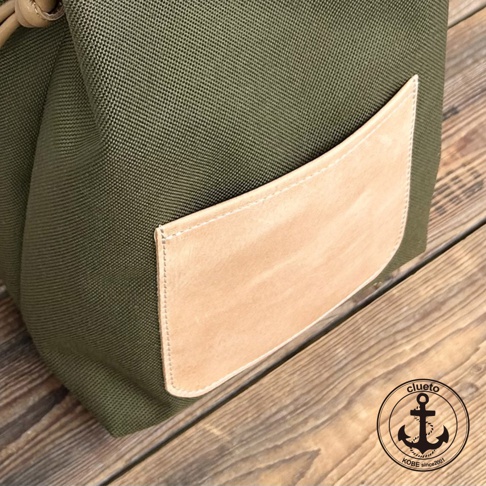 神戶clueto品牌綠色防潑水尼龍束口包，附有義大利皮革前袋，右下角有品牌錨形標誌，標示KOBE since2001