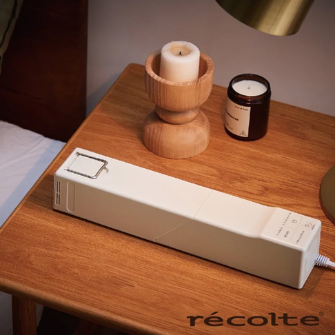 recolte 奶油白烘被機 RFK-1 放在木質床頭櫃上，旁邊有木製燭台和黑色罐裝香氛蠟燭