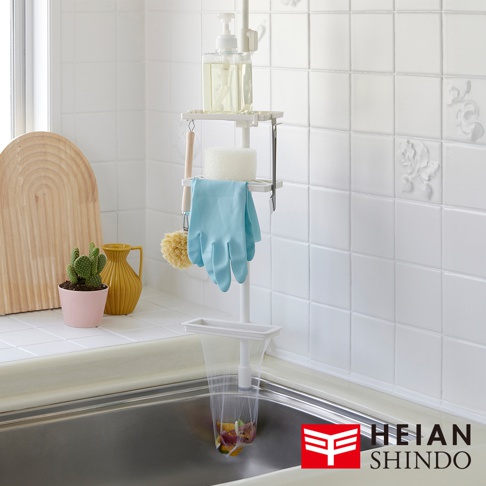 白色直撐式濾網架，上方掛有洗碗精瓶、海綿、藍色手套和清潔刷，下方則掛有裝有廚餘的濾網袋，架子立於廚房水槽旁。