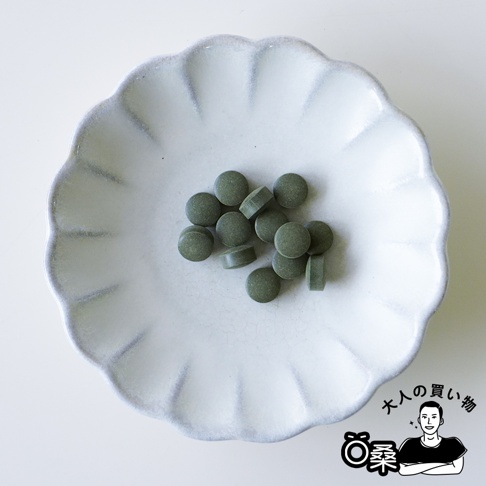 盤子裡有綠色的錠狀物，右下角有「大人的購物」的日文文字和一個黑色剪影圖案。