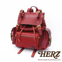 酒紅色皮革復古風旅行後背包，設有側邊口袋、束繩開口和多個金屬釦環。