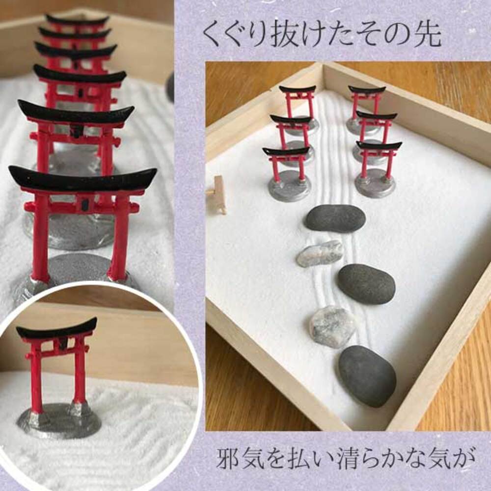 此圖片展示一個日本枯山水模型，以白色細沙為底，擺放著數個紅黑色的鳥居，鳥居下方為灰色底座。部分鳥居旁點綴著大小不一的灰色石塊，整體呈現簡約的日式庭園風格。