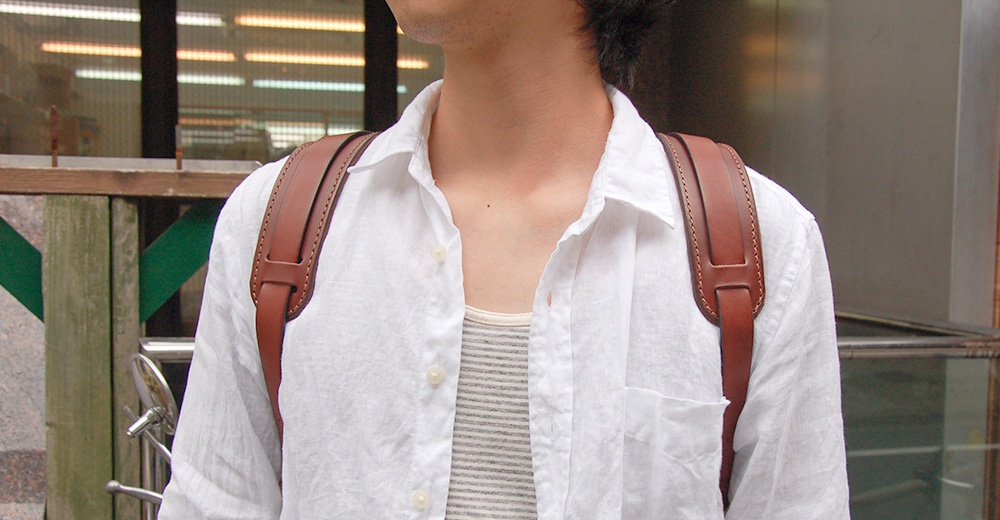 職人手作皮革Big肩墊，咖啡色皮革，搭配白色長袖襯衫，展示於肩部。