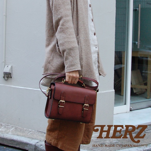 職人手作皮革迷你兩用包，深棕色，帶有雙皮帶釦設計，可手提或斜背。