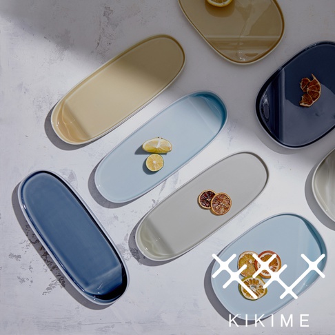 多個長型波佐見燒主菜盤，顏色包含深藍、淺藍、米白、卡其黃，部分盤子上有檸檬片或乾燥柑橘片裝飾。