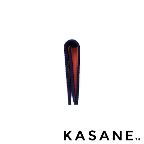 KASANE 品牌標誌旁的午夜藍色皮革長夾，內層為橘棕色，從側面拍攝，展現其層疊結構。