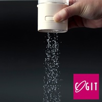 手持一罐米白色塑膠材質的定量灑鹽罐，罐身有按壓按鈕，正定量地灑出細小的白色顆粒，背景為深色。