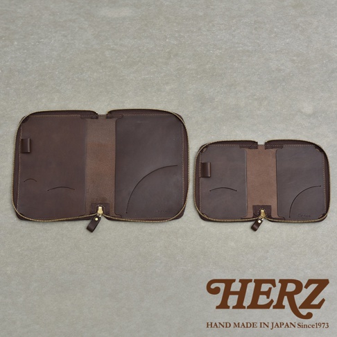 兩個棕色皮革製的拉鍊式收納包，分別為較大和較小的尺寸，內側有夾層和筆插，底部有品牌Logo。