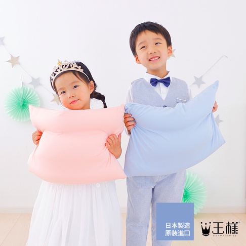 一對孩童，女孩穿著白色公主裙頭戴皇冠，抱著粉色枕頭；男孩穿著西裝打著領結，抱著淺藍色枕頭。