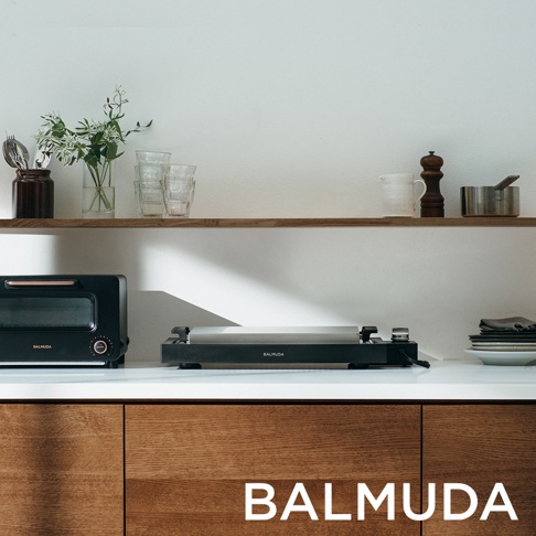 The Plate Pro 極致電烤盤 (黑色)，配備光滑的黑色機身和銀色烤盤，置於白色檯面上，旁邊是另一台黑色烤箱。