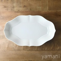 淡青白釉美濃燒輪花長盤，以陶瓷製成，呈現柔和的白色調，盤緣帶有輪狀花瓣紋飾，中央有八角形凹槽，置於木紋背景上。