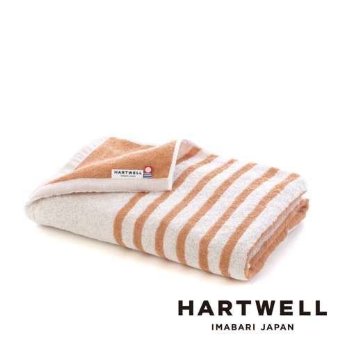 一條今治製棉質浴巾，米白色底布搭配橘色條紋，標籤顯示「HARTWELL IMABARI JAPAN」。