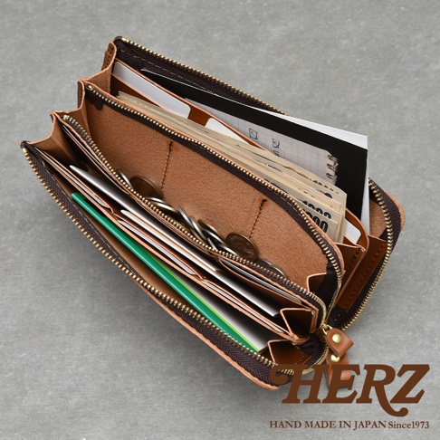 職人手作皮革Organ拉鍊長夾，內部展示，裝有紙鈔、零錢、卡片和筆記本，採用天然皮革材質，深棕色拉鍊，整體呈現大容量收納的實用性。