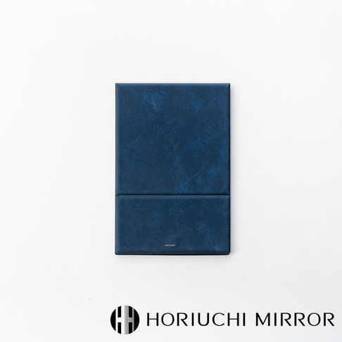 NAPURE 桌上型2Way折疊化妝鏡，深藍色皮革紋理外殼，可折疊設計，中間有細微的摺痕，上方印有小字品牌標誌。