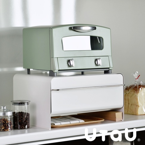 白色抽屜式收納櫃，上層放置薄荷綠色烤箱，櫃體前方有銀色金屬把手，下方抽屜內有格子布墊與木盤。