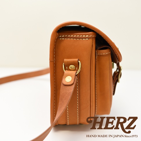 HERZ 品牌經典手工皮革郵差包，側邊視角，附有金屬扣環和皮質背帶
