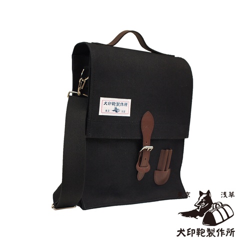 黑色純棉帆布製成，直式側背包，附有棕色皮革翻蓋扣帶、提把和可拆卸肩帶。包包正面中央有一個粉紅色標籤，印有日文文字和圖案。