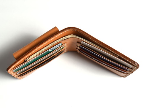 棕色皮革雙折短夾，外側附有零錢袋，夾內插有多張信用卡和紙鈔。