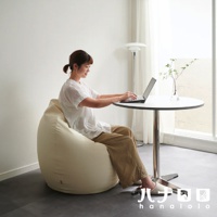 女性坐在米白色皮革款懶骨頭沙發上，使用筆記型電腦。沙發體積龐大，呈圓潤的玉子形狀。