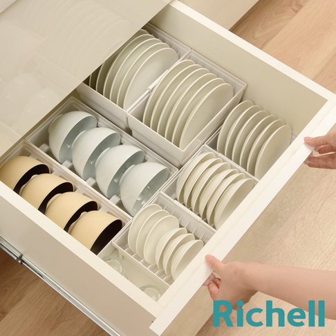 抽屜式餐盤收納架整齊擺放著白色盤子和碗，部分碗為米黃色，收納架為白色。