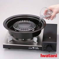 卡式爐專用網狀烤盤，黑色金屬材質，帶有銀色支架。網狀烤盤中央有水，一隻手正在往烤盤中倒水。