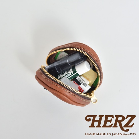 職人手作皮革三角飯糰造型小物收納包，棕色皮革材質，拉鍊開口，內含護唇膏、藥品等小物。