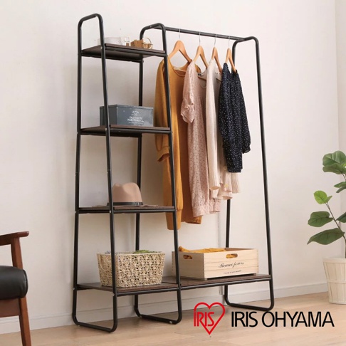 黑色金屬框架搭配木紋層板，設有吊衣桿及四層收納空間，展示有黃色、粉色、米白色及黑色印花衣物，下方擺放帽子、編織籃和木盒。