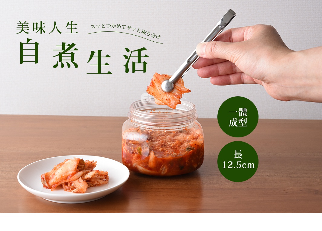 一只手正使用不鏽鋼萬用料理夾夾起醃漬的泡菜，旁邊有一個裝有泡菜的透明罐和一個裝有泡菜的小盤子。