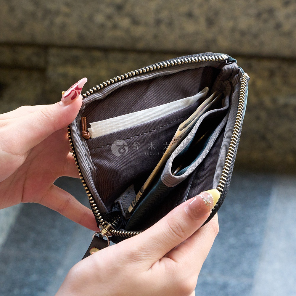 TUTUMU 防潑水迷你錢包，由女性雙手打開，展示內部有日圓鈔票、硬幣和卡片。