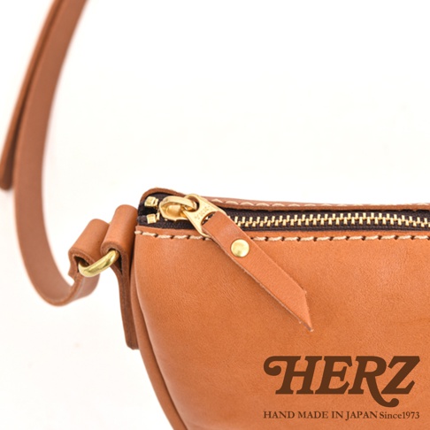 HERZ 品牌皮革半圓包的特寫，展示了拉鍊、皮革細節及日本製造標誌