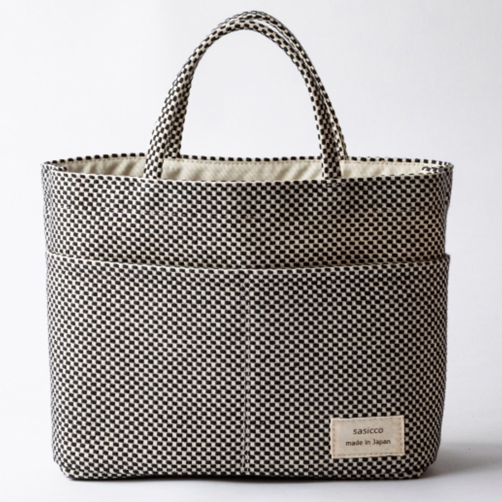 三河木綿刺子織多口袋托特包，黑白格紋圖案，棉質材質，附有兩個前袋和兩個側袋，搭配兩條圓形提把，內襯為米白色。