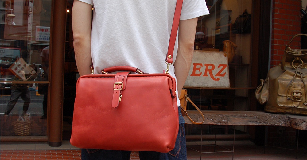 一個紅色皮革手提包，配有可拆卸肩帶和金色搭扣。