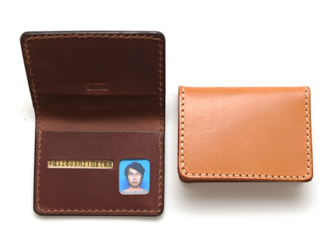職人手作皮革雙折證件收納夾 (KC-43)，包含一個打開的深棕色皮革證件夾，內有卡槽、證件照及日文標示，以及一個閉合的淺棕色皮革證件夾。兩者均採用手工縫線。