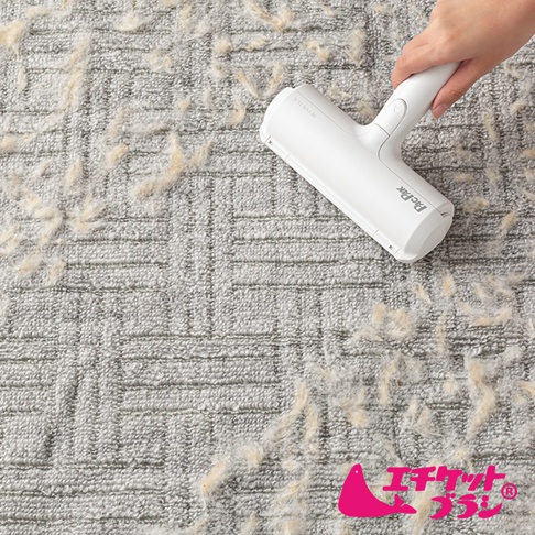 白色可水洗免耗材清潔滾輪，正在清理淺灰色布料上的毛絮。滾輪具備人體工學手柄，表面印有「PicPic」字樣。