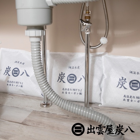 車內專用方形調濕木炭，白色包裝袋印有黑色「炭八」字樣及日文說明，下方有灰色波紋軟管和銀色金屬支架。