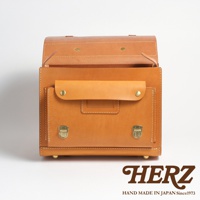 職人手作皮革橫式書包，自然光澤的淺棕色皮革，正面有翻蓋口袋和金屬鎖扣，整體風格簡約復古。