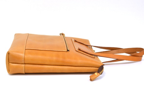 棕褐色皮革製作的直式拉鍊托特包，有明顯的縫線細節，正面有一個拉鍊口袋，配有兩個皮革提把。