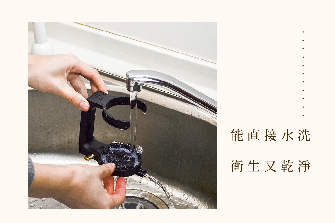 雙手正在清洗黑色的啤酒金泡機，水流從水龍頭流下，沖洗著金屬和塑膠材質的機身，下方有細密的黑色網狀結構。