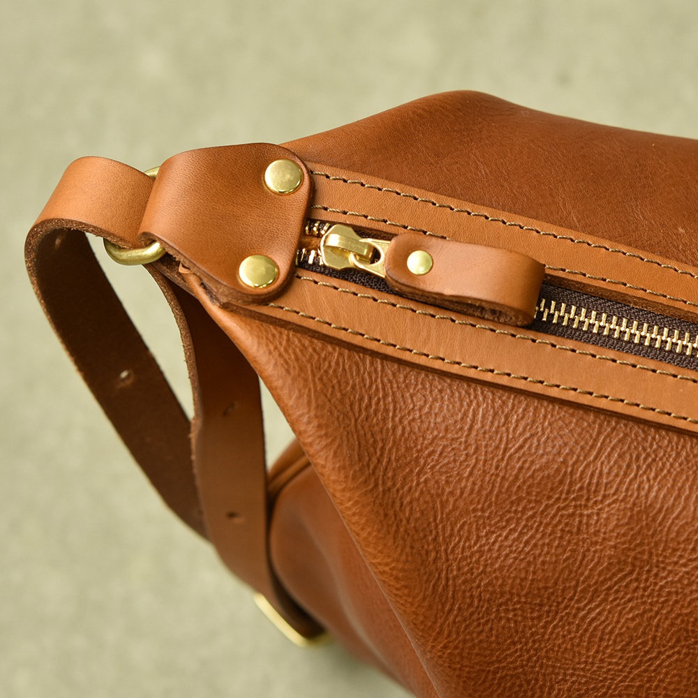 職人手作皮革Organ單肩半月包，採用棕色皮革，配有金色拉鍊和鉚釘，展現其精緻工藝與質感。