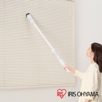 白色超輕量多合一手持無線吸塵器，長柄設計，前端裝有黑色刷頭，正被一名女性用於清潔米白色百葉窗。